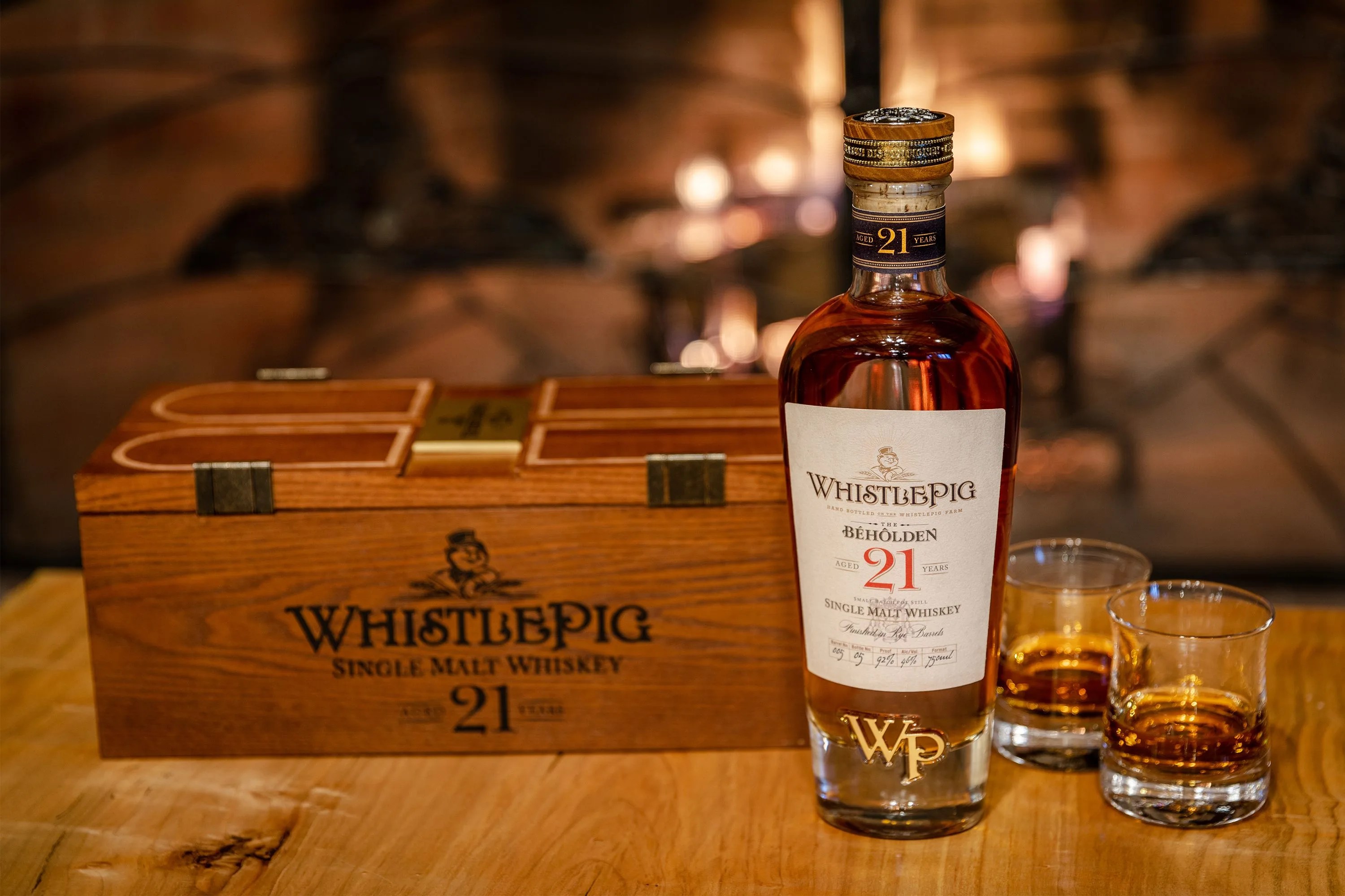 whistle pig whiskey bottle, wooden case, and tasting glasses on a table