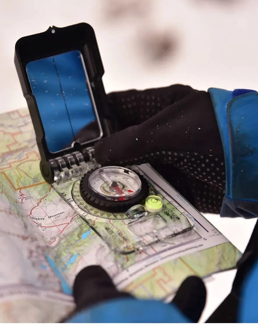 person hodlding up brunton truarc 15 luminous compass against map