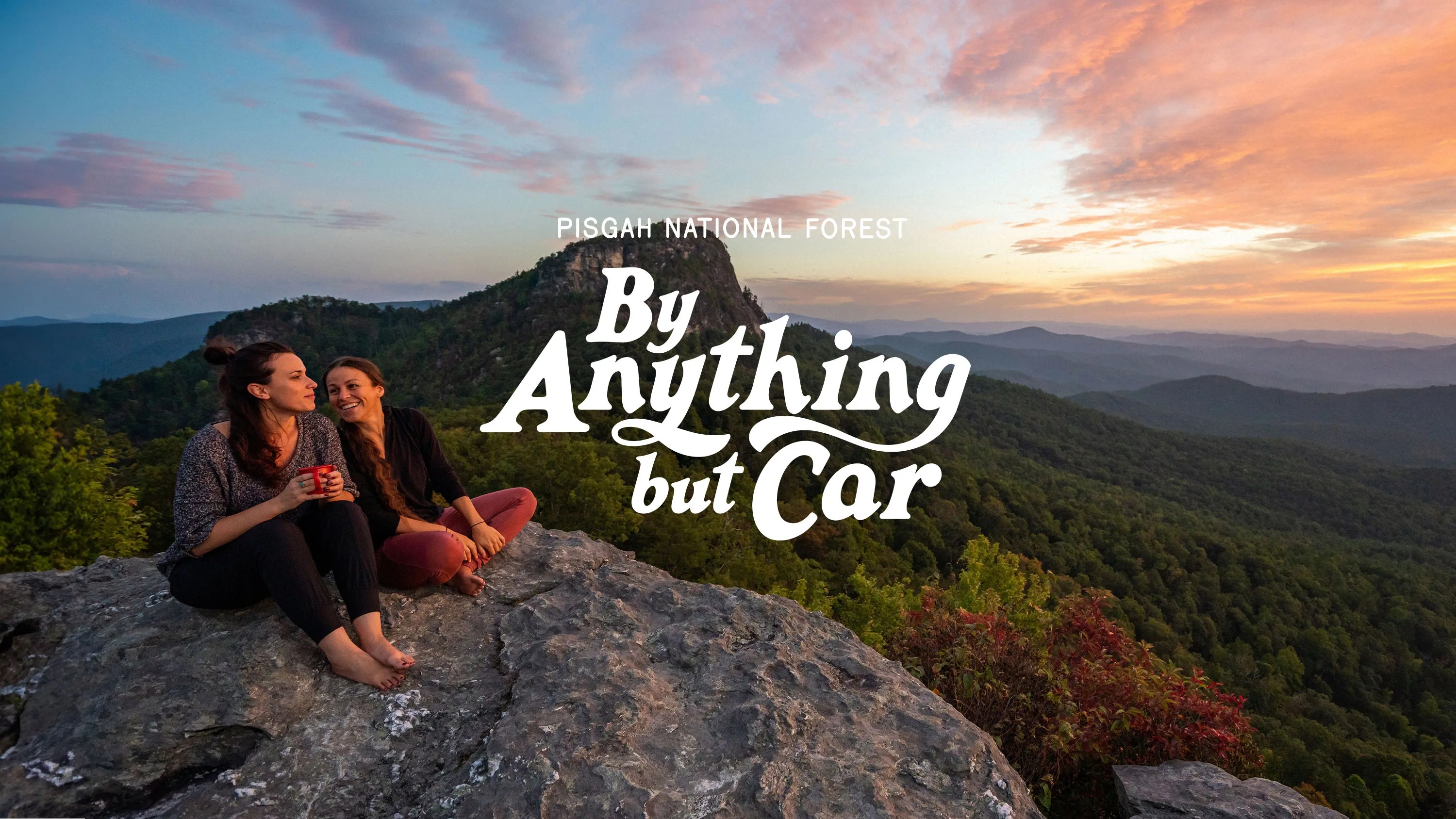 by anything but car two women sitting on a rock overlooking pisgsah national forest