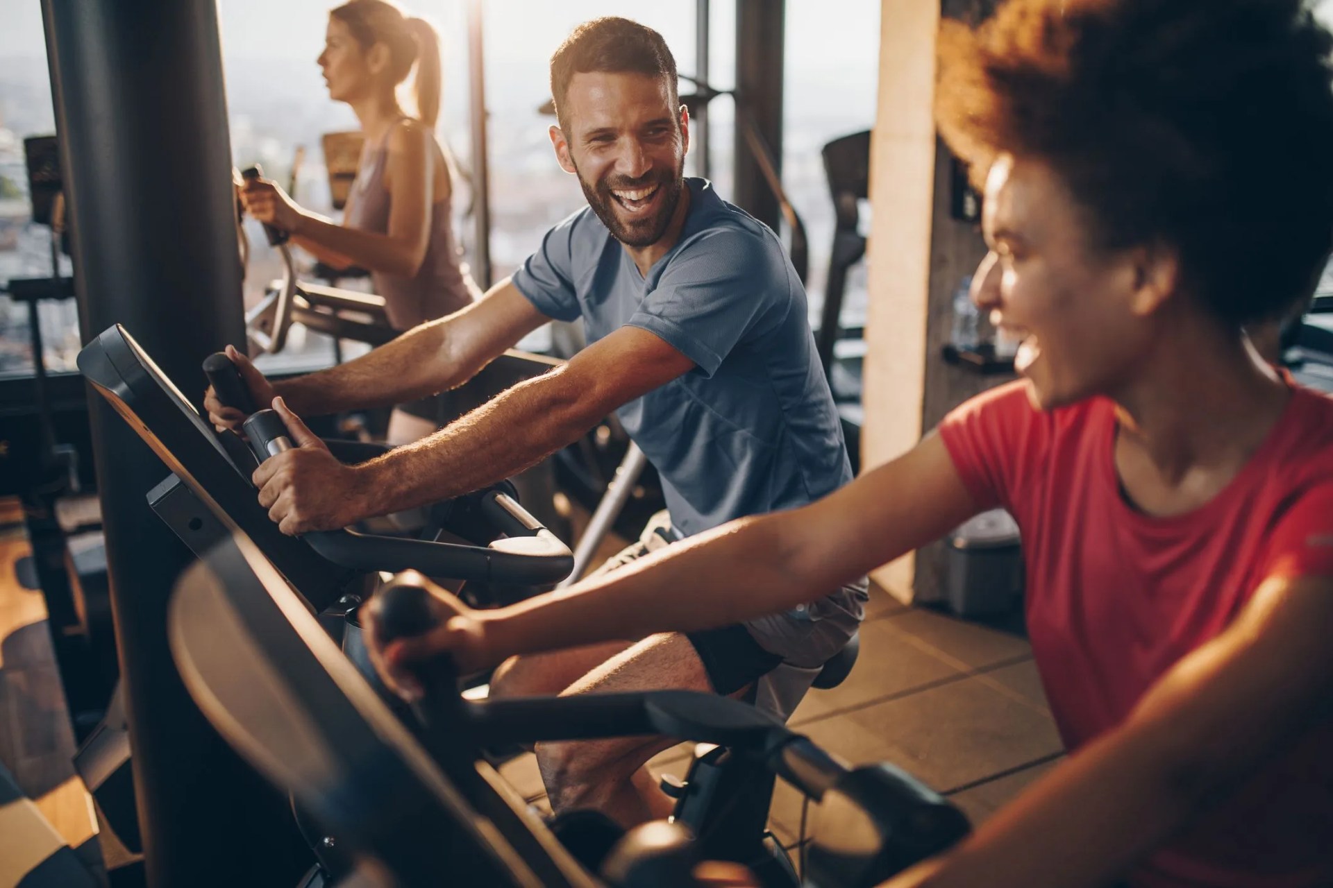 cheerful male athlete talking to his friend on exercising training in a health club