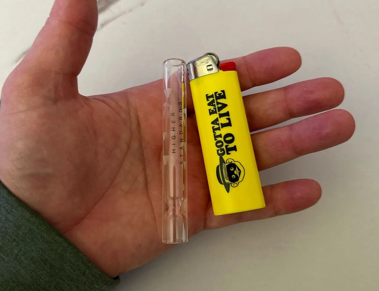 a higher standards chillum in a a hand with a lighter