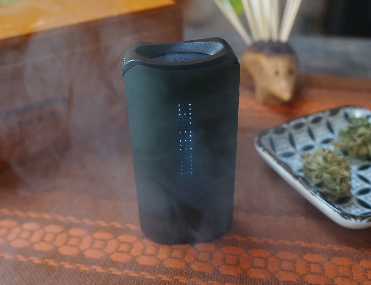 a green davinci iqc place on a table with smoke leaving it's mouthpiece