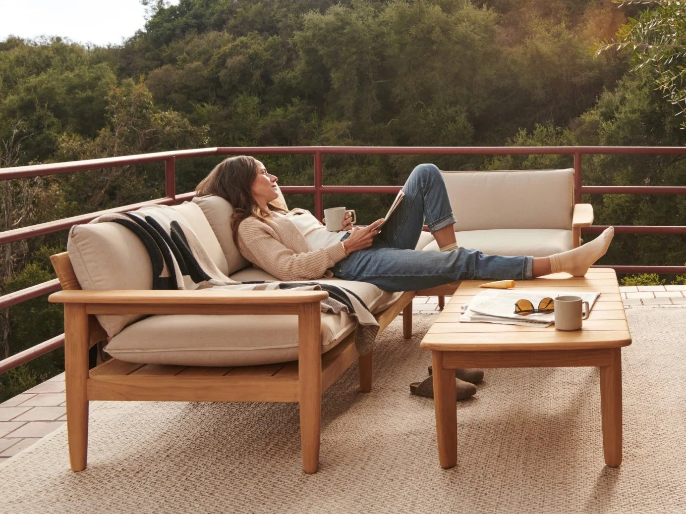 Woman sitting on Burrow Dune love seat sectional on porch with view of trees