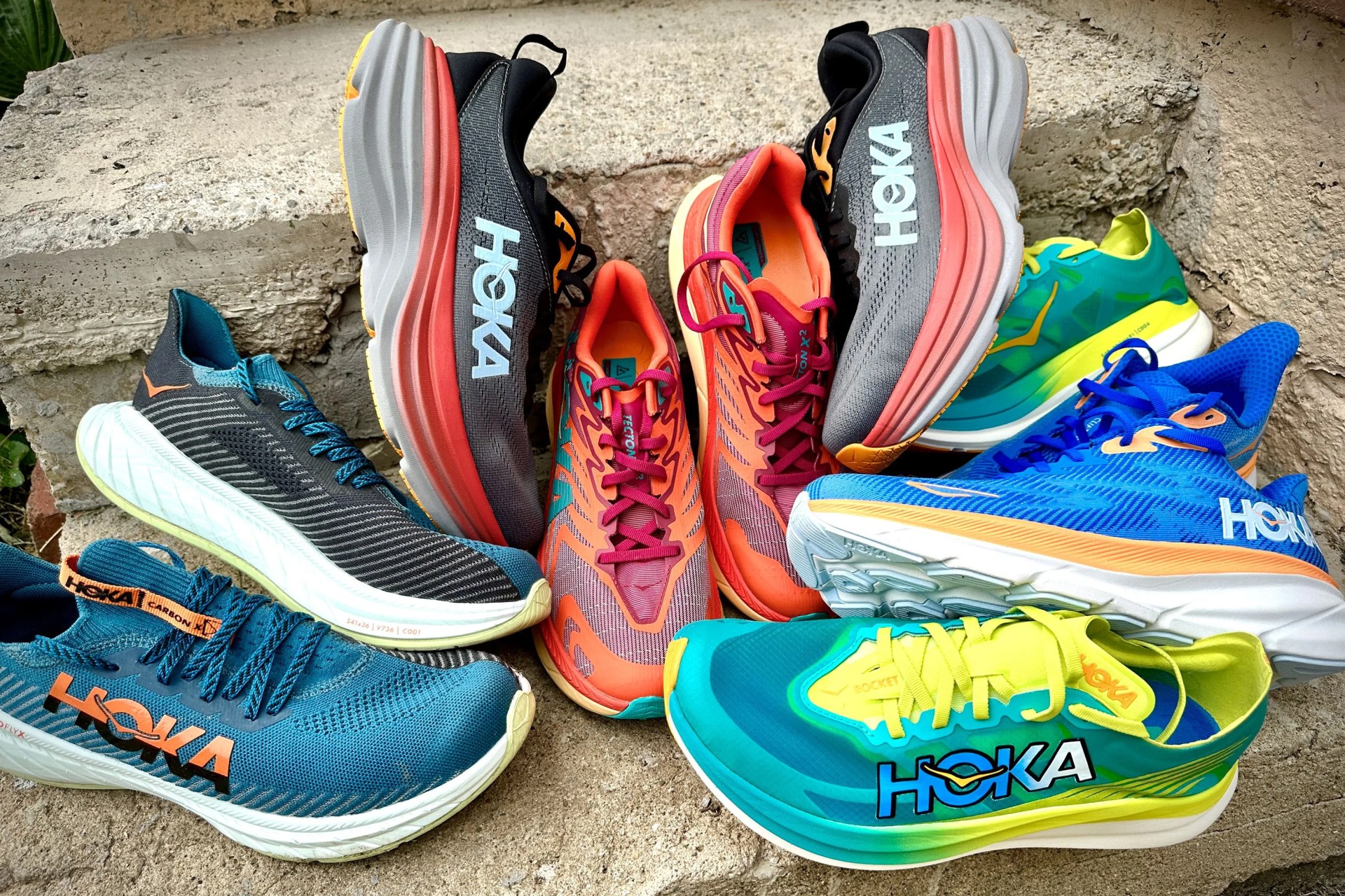 a variety of hoka running shoes on cement stairs