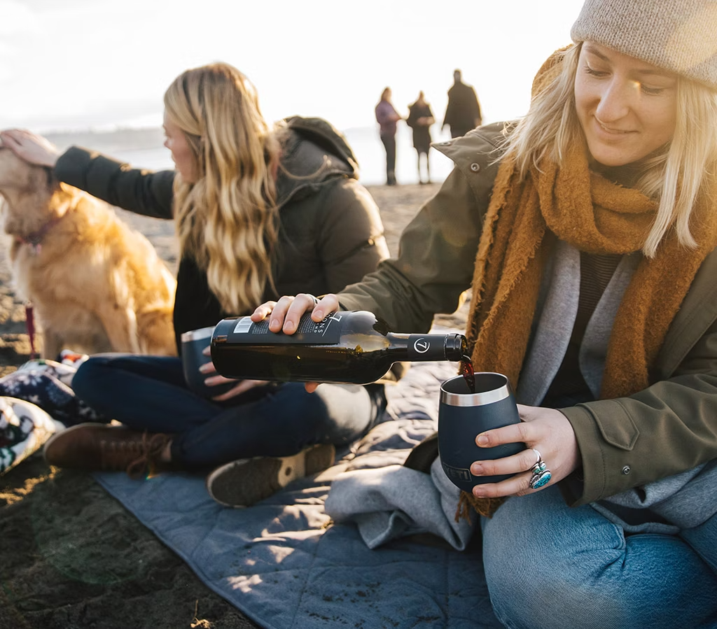 person pouring wine into yeti tumbler