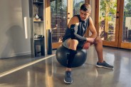 a man sitting on an exercise ball wearing the therabody recoverypulse collection