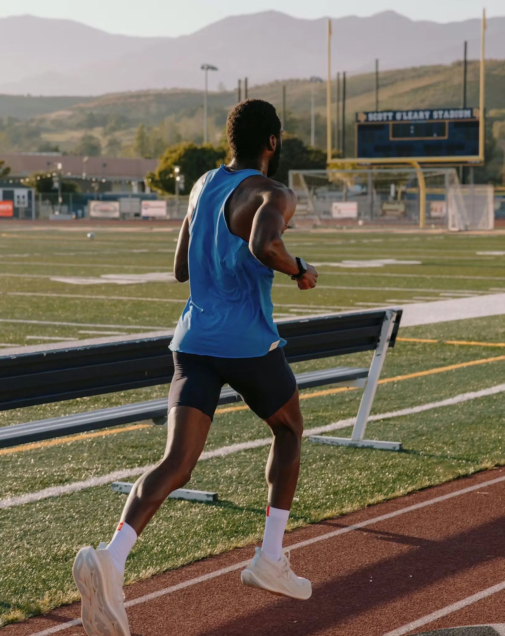 man running on track and field wearing strata collection from track smith