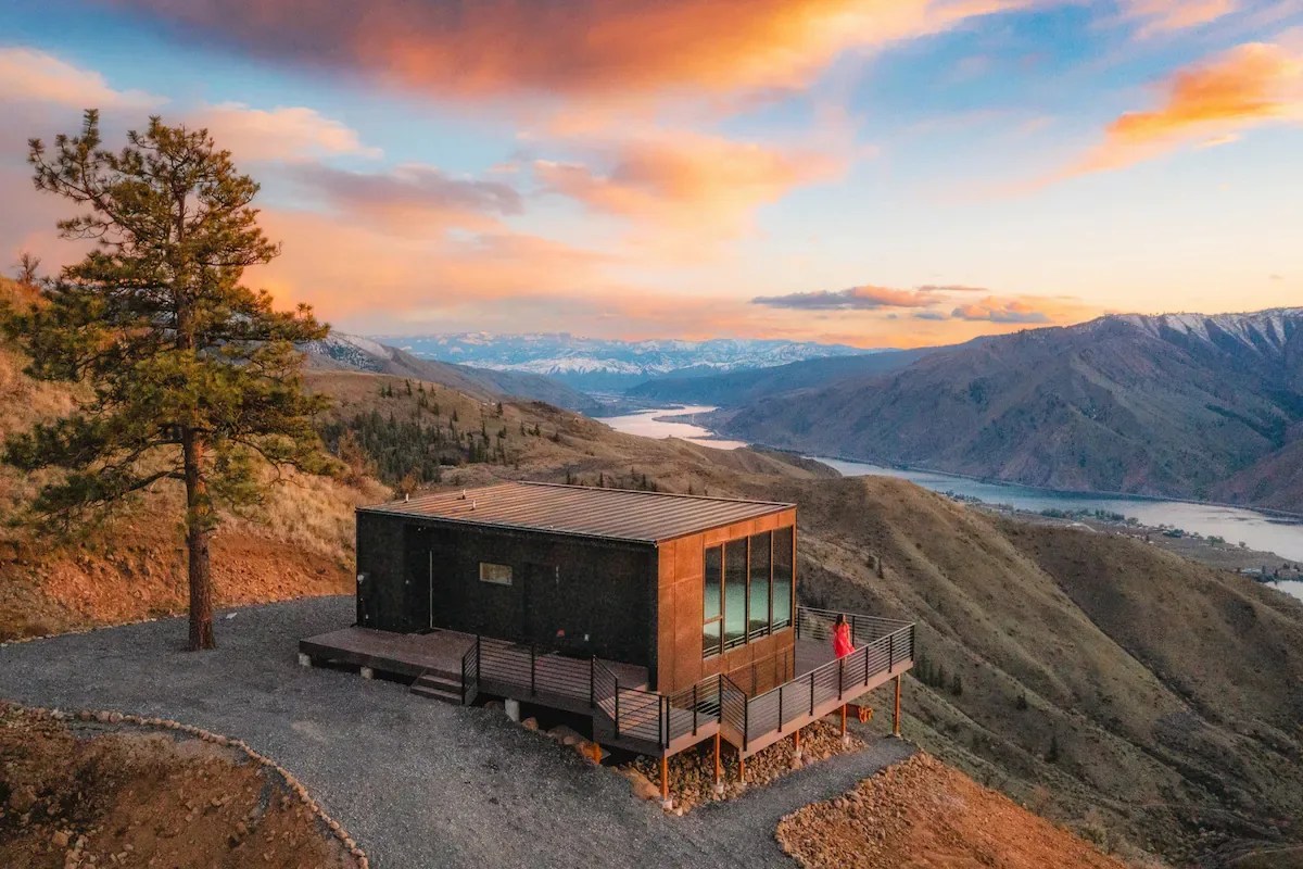 a modern cabin perched on a mountaintop at sunset