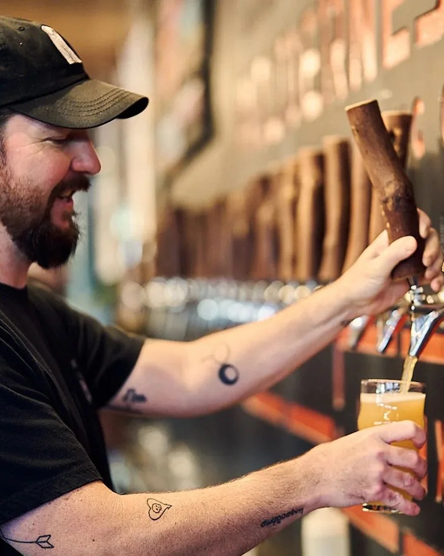 man filling up cup with beer from tap