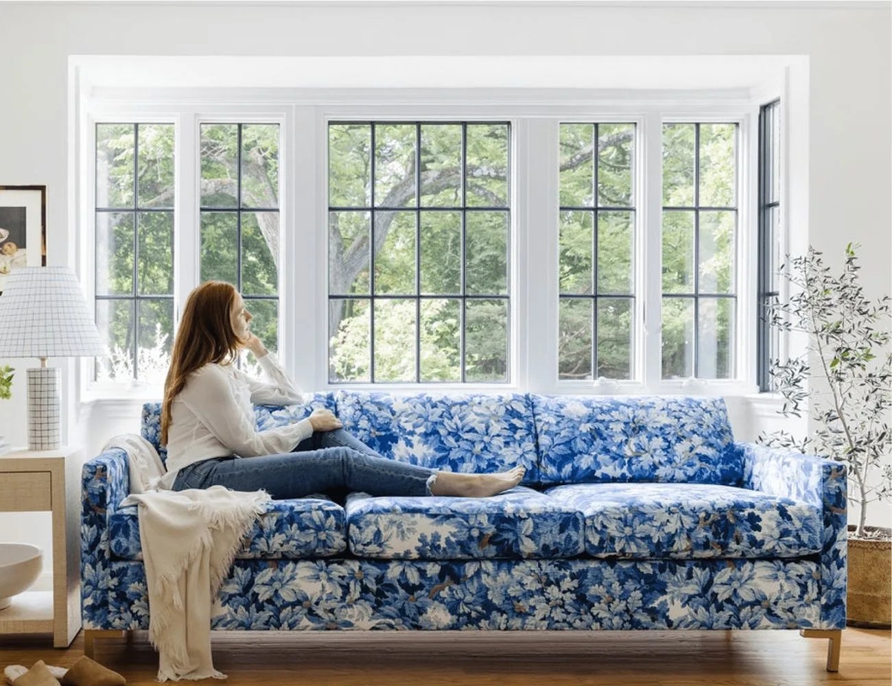 a woman sitting on a blue floral couch