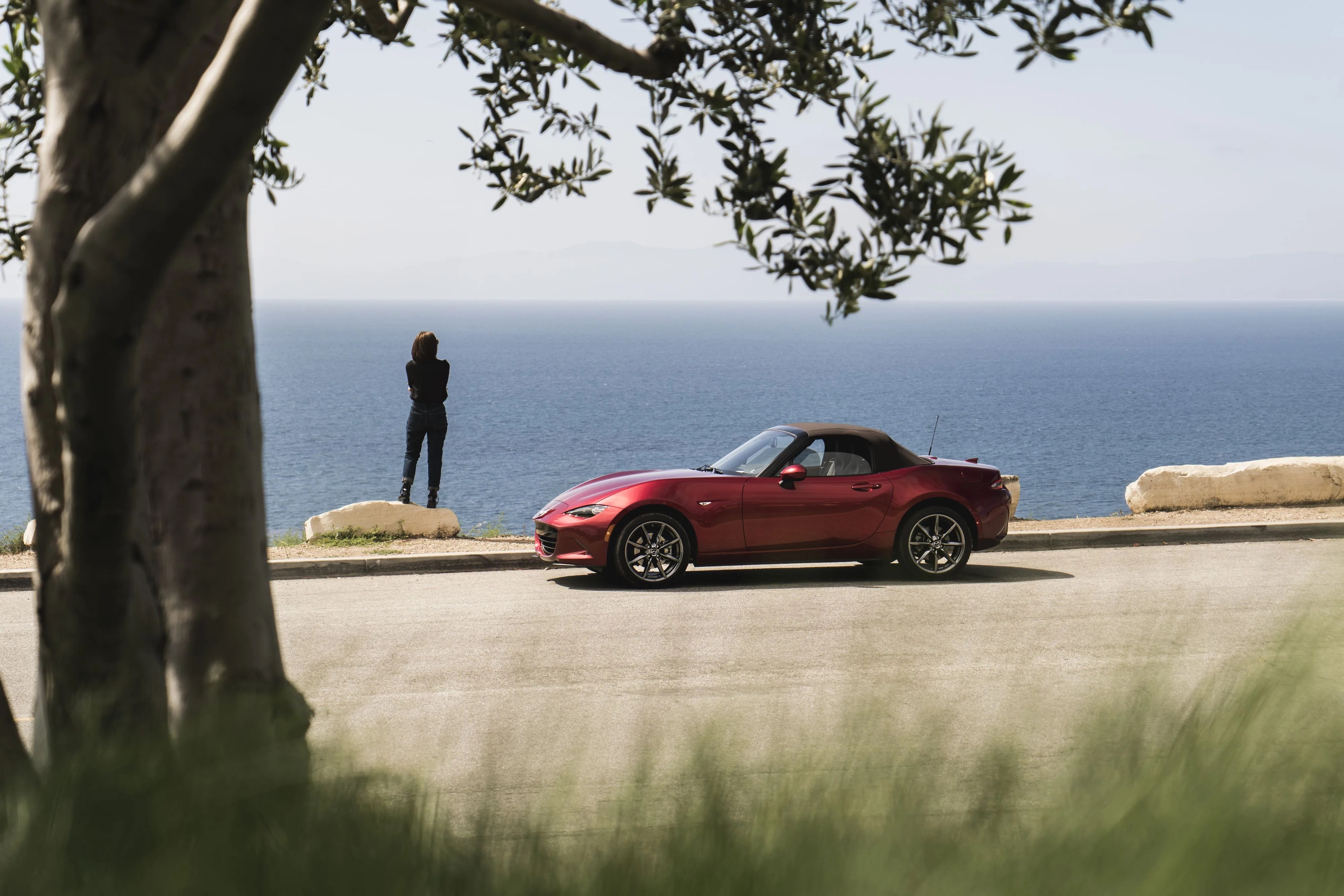 mazda miata parked next to the ocean