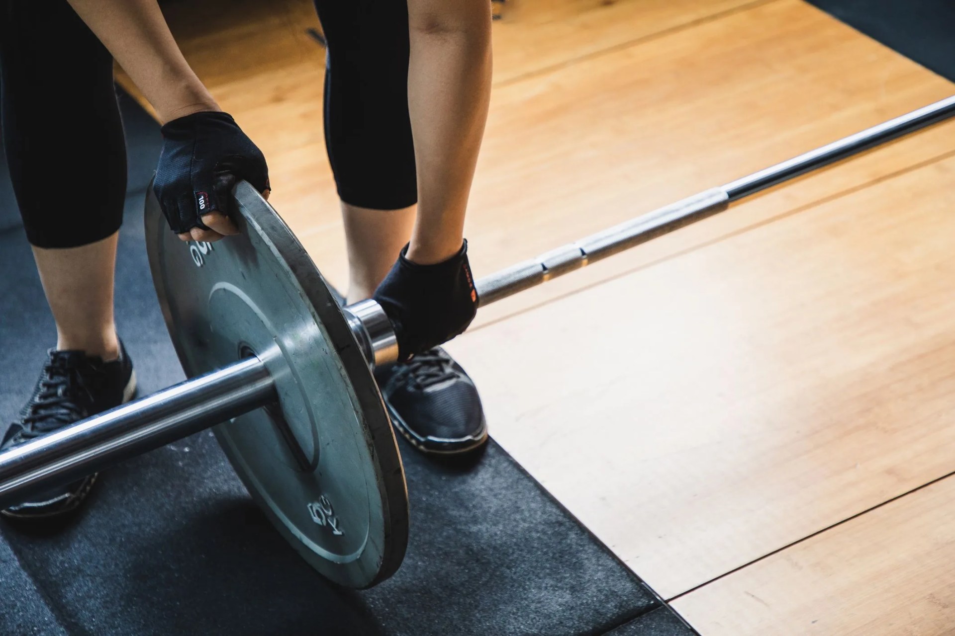 asian woman lifting weights in a gym changing barbell weight plate