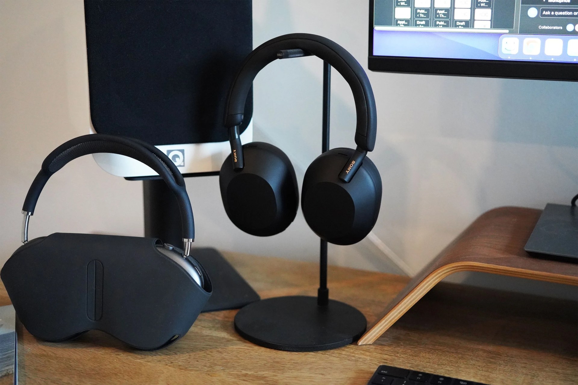 two headphones in headphone stands on a desk