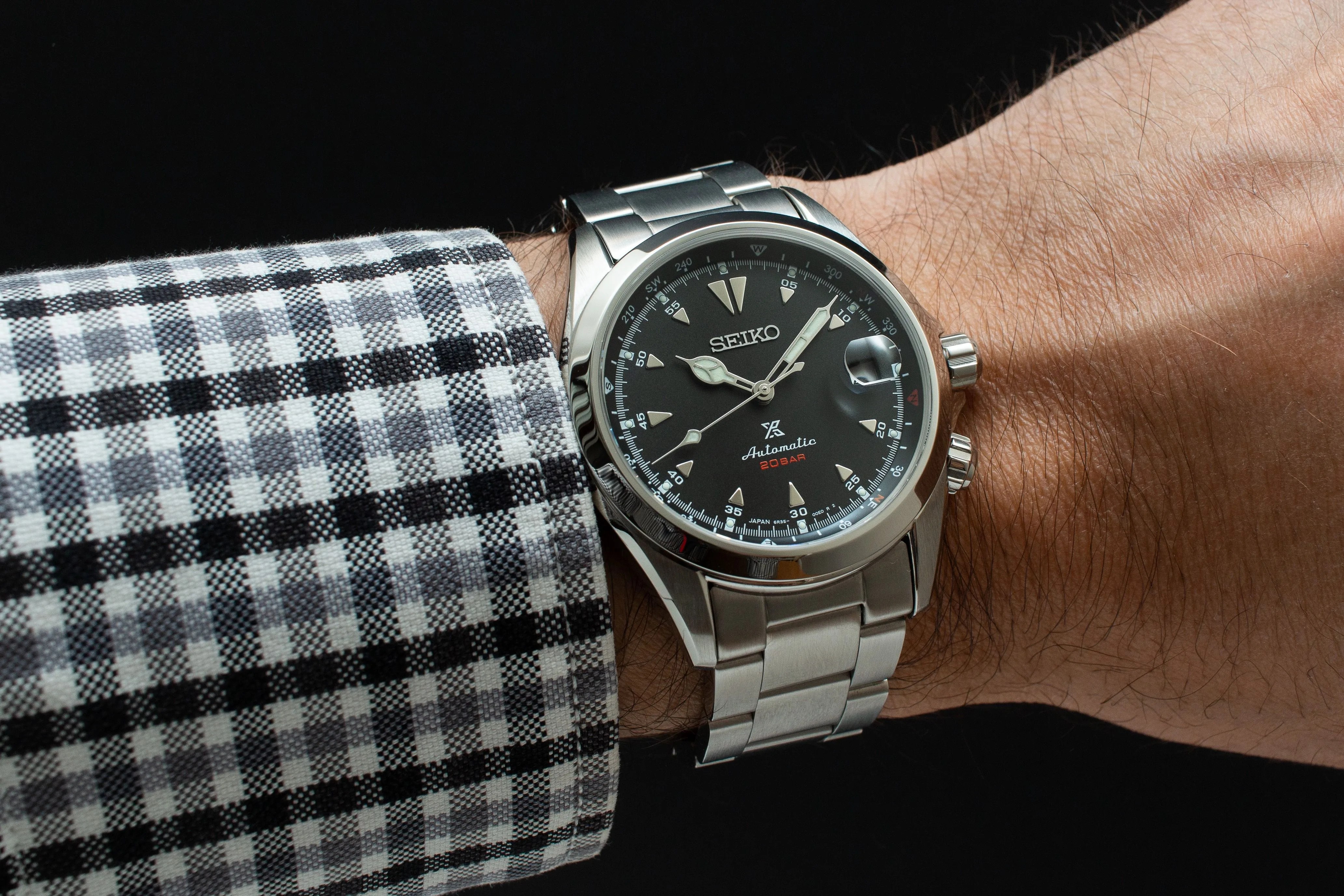 steel watch on wrist with checkered shirt