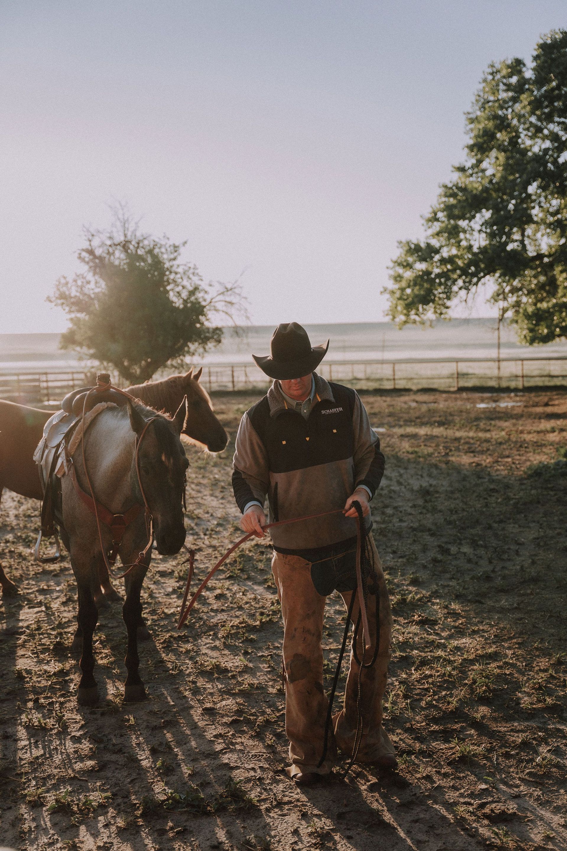 man leading horse in ring wearing schaefer outfitter pullover