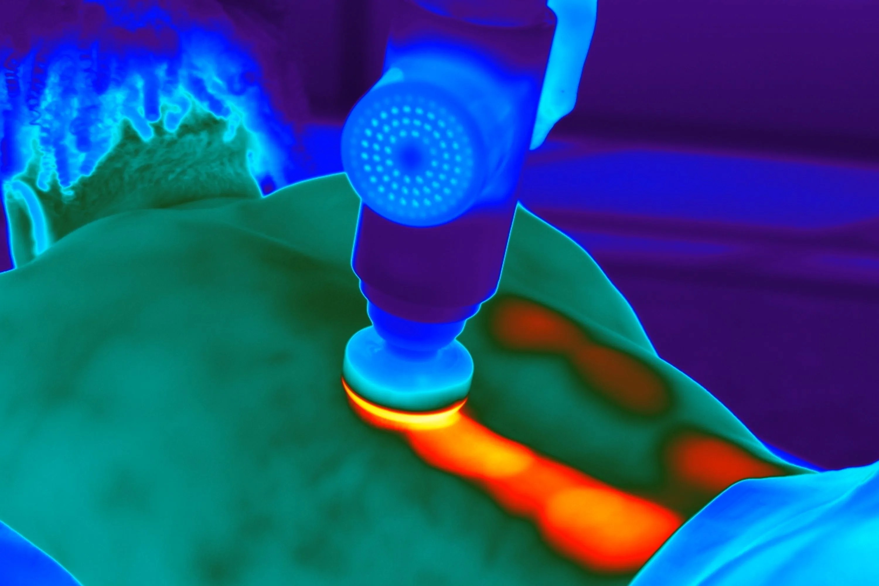 an infrared photo of a person getting a back massage with a hypervolt heated massage gun