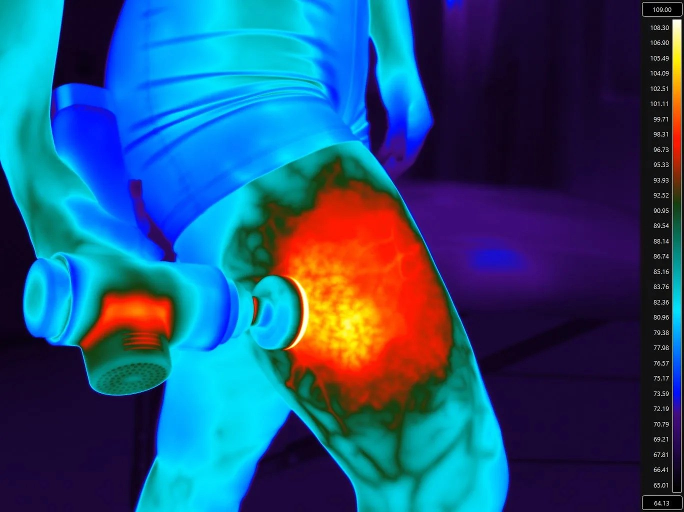 an infrared image showing someone using a heated massage gun on their thigh