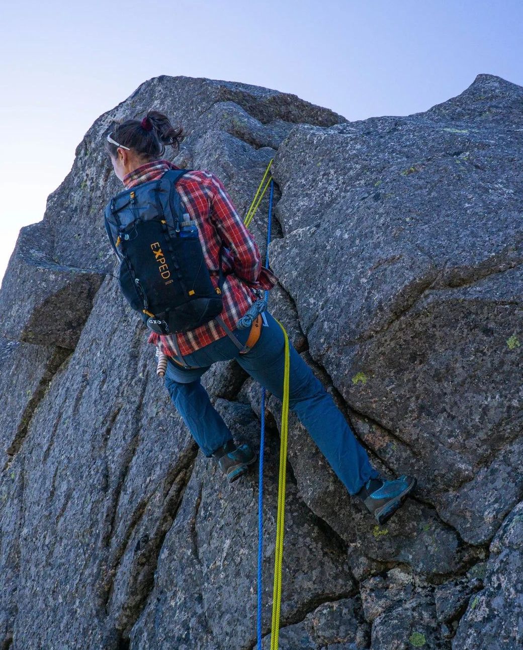 woman climbing cliffside wearing exped impulse 20 backpack