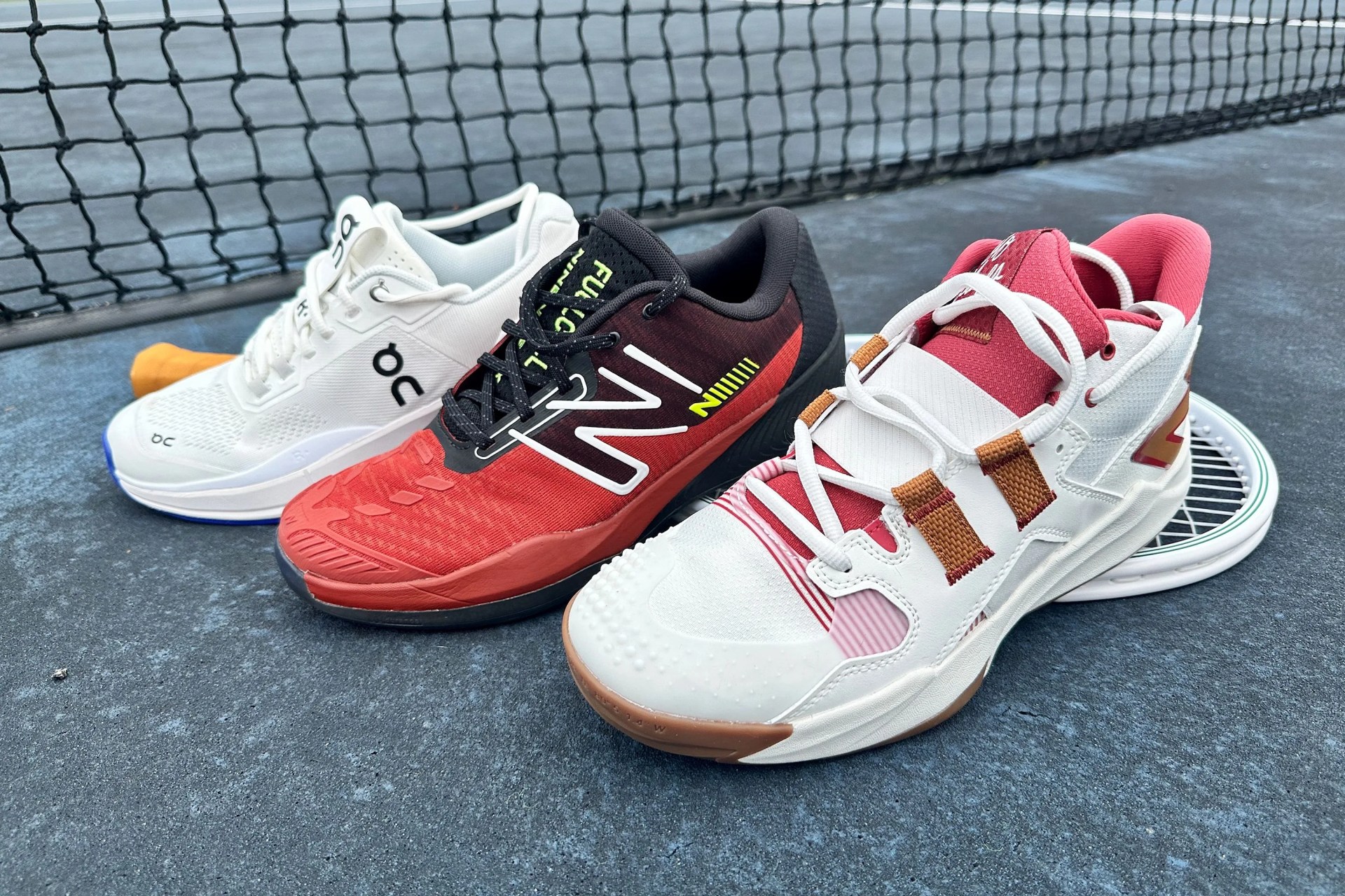 three tennis shoes on a tennis court