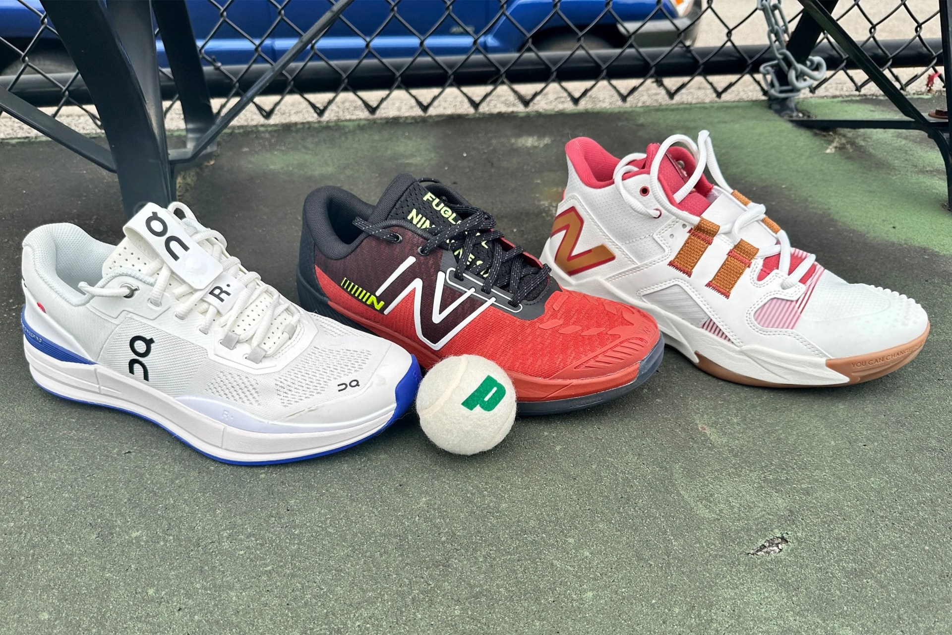 three tennis shoes on a court with a tennis ball