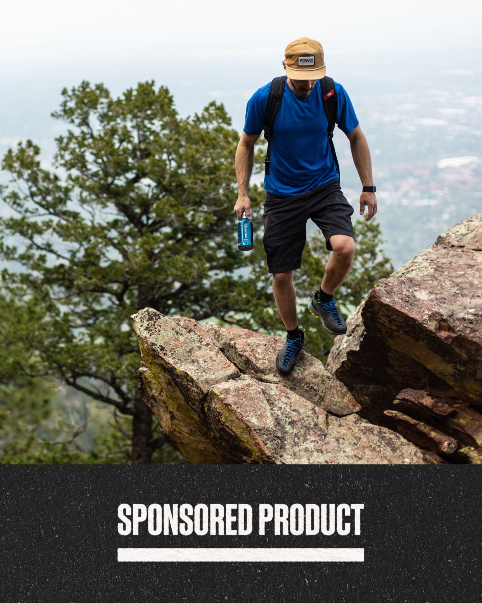 sponsored product man holding tincup whiskey while hiking on cliff