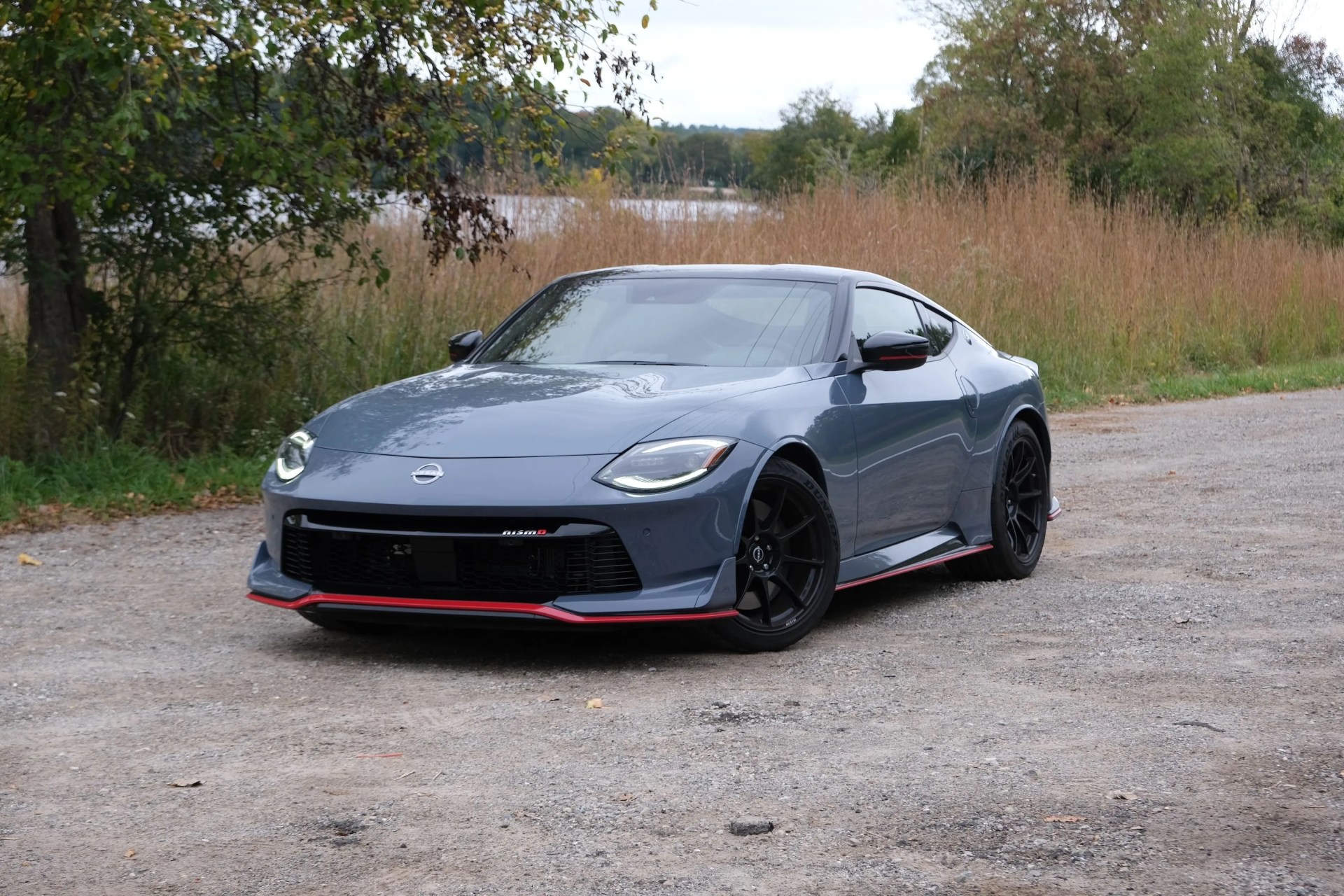 a black sports car parked on a road near trees and grass