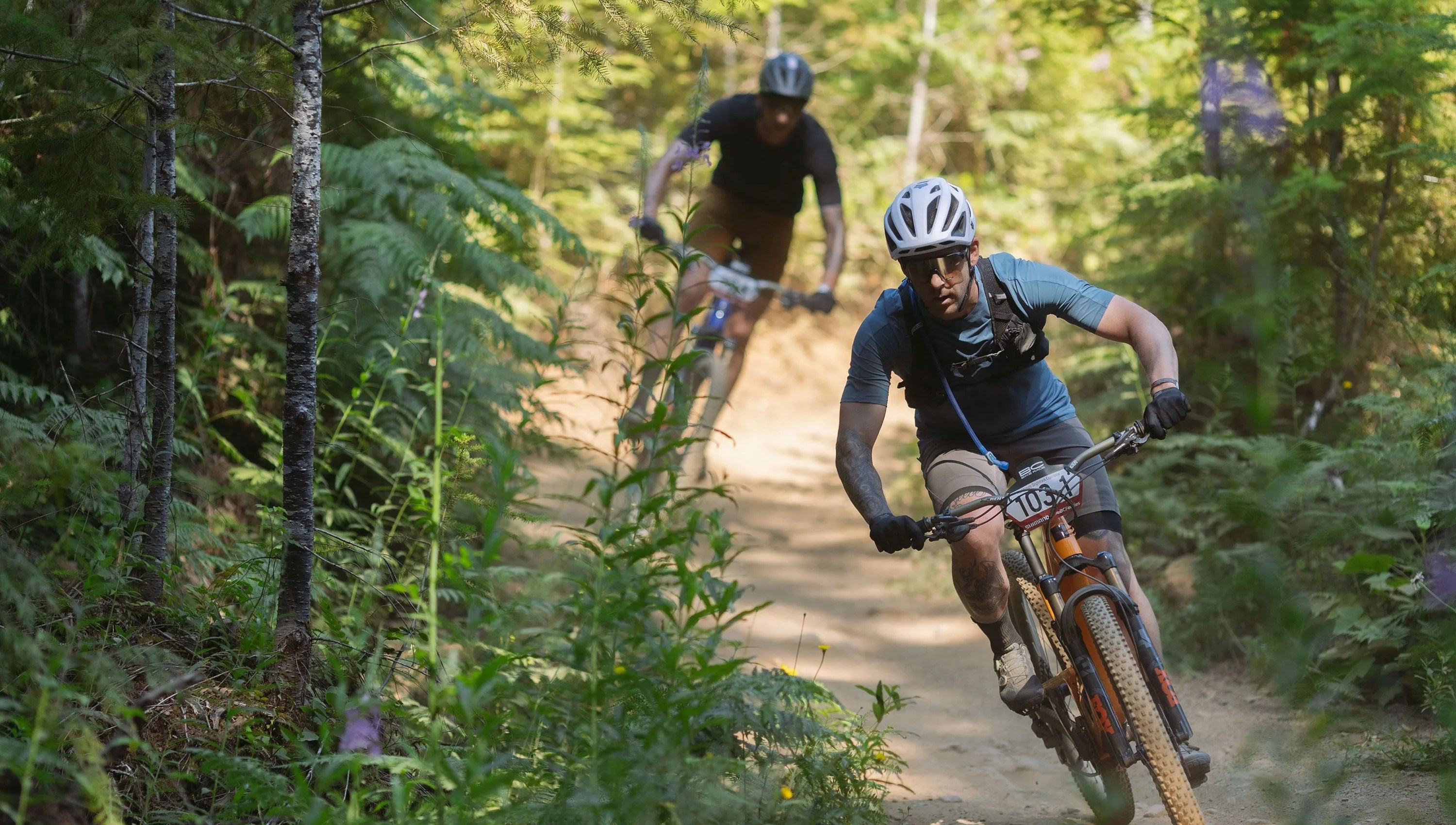 men riding bikes wearing fox facing cross frame pro helmet and flexor ascent clothing