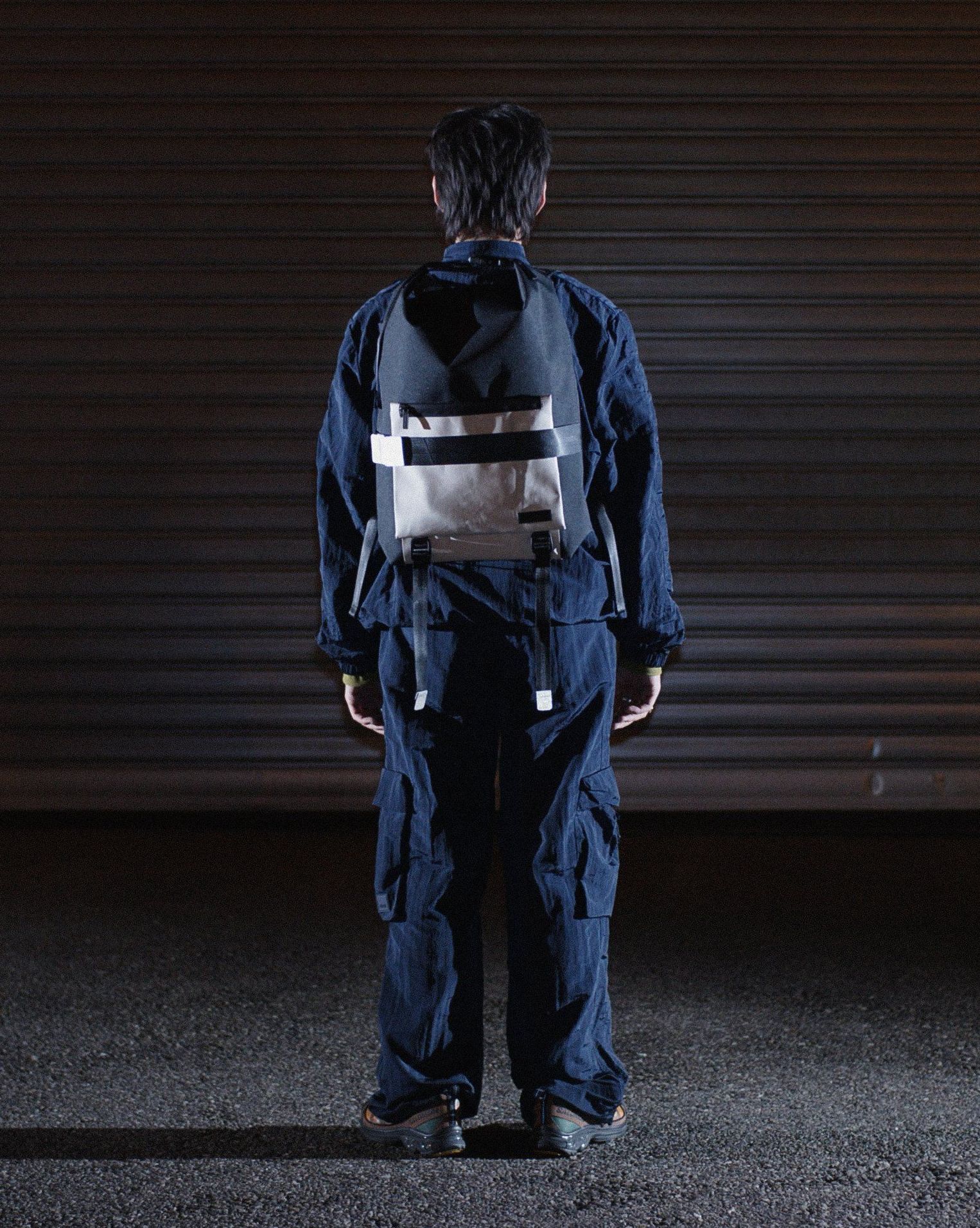 a man with his back facing towards you wearing freitag reflective backpack