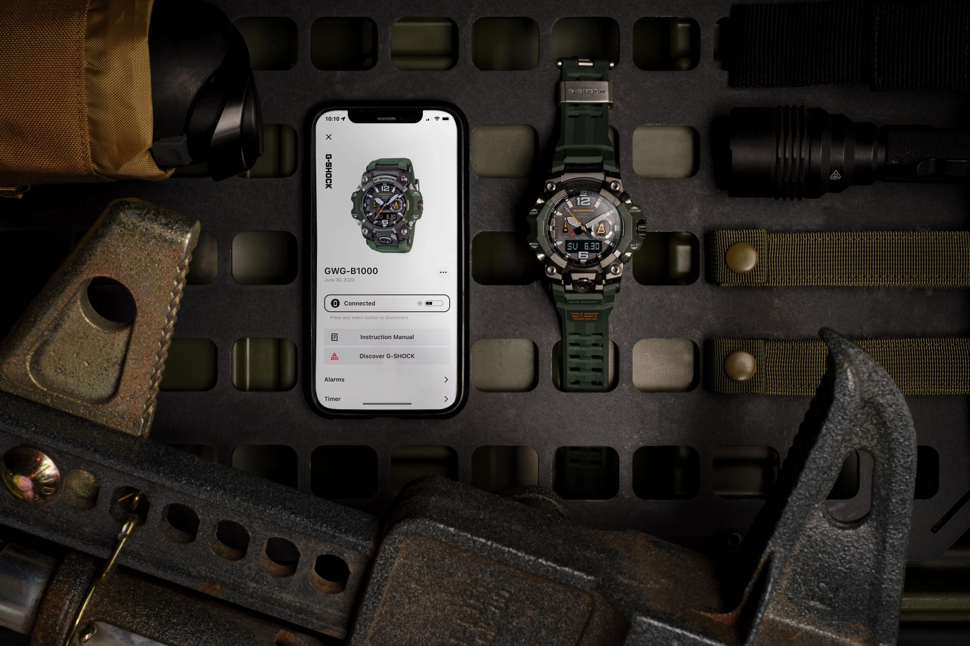 casio g shock watch laying next to phone and tools on a metal grate