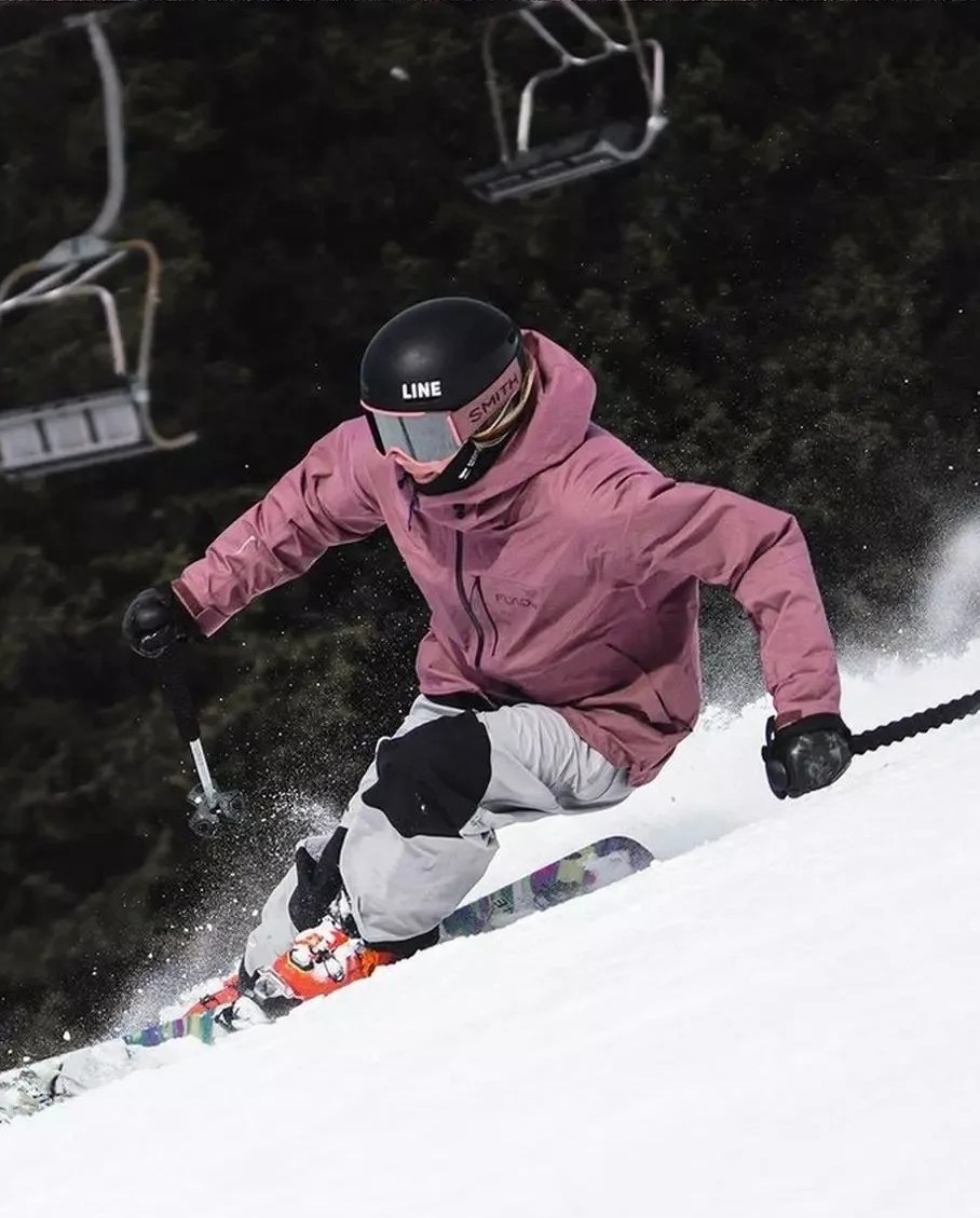 a woman skiing down a snowy hill wearing pandora skis