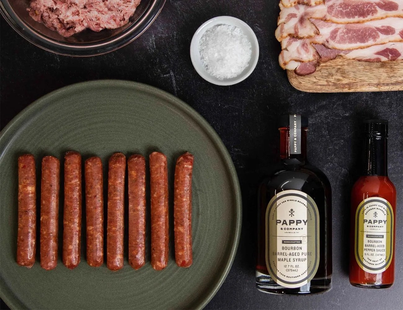 a plate of hot dogs and bottles of sauce on a table