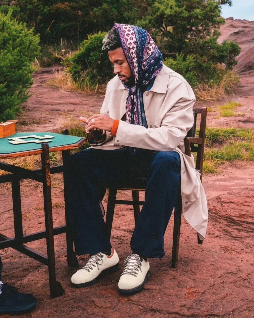 a man sitting at a table outside wearing merrell wilderness 1trl shoes