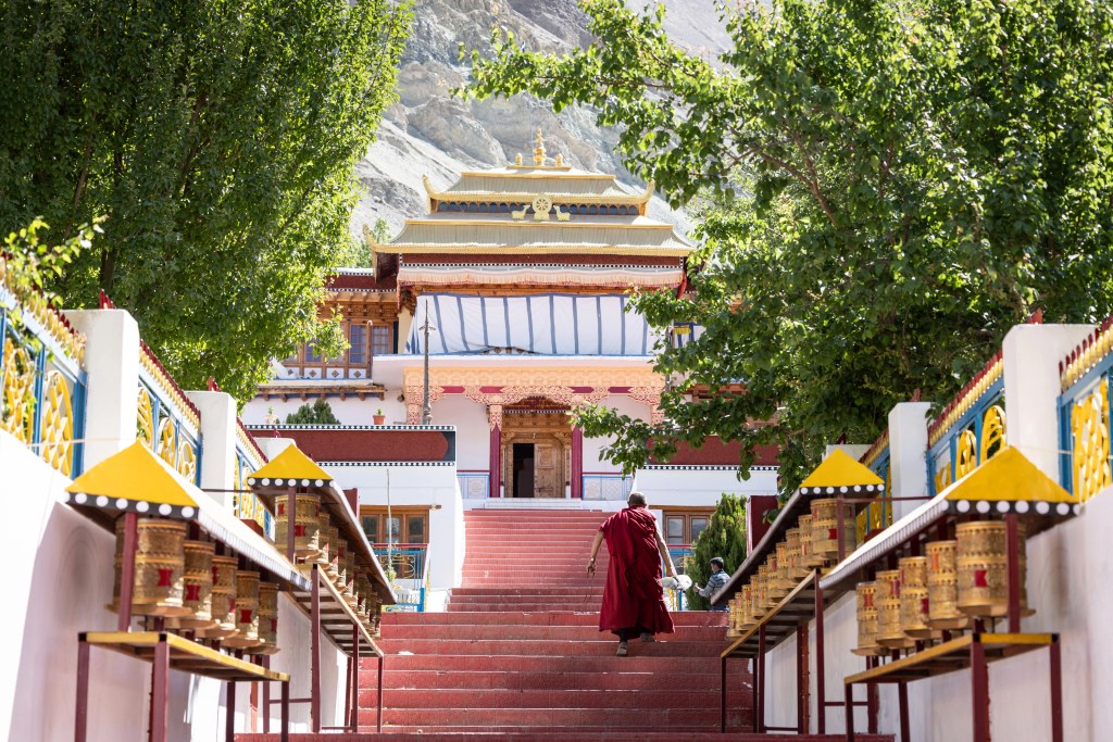 a monk walking up the stairs of a buddhist temple