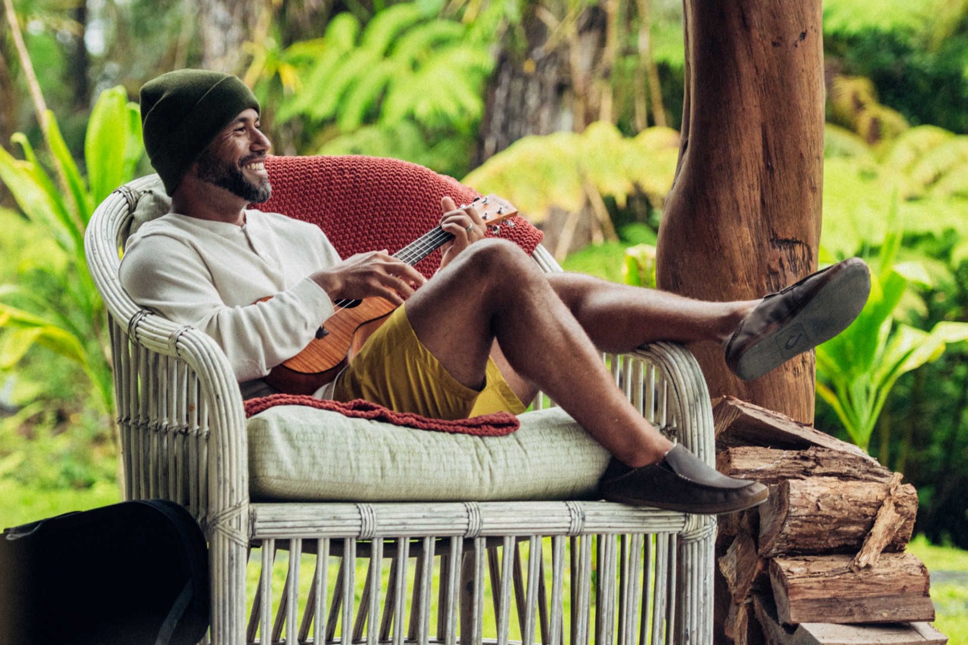 man sitting in chair with ukulele wearing olukai moloa slippers