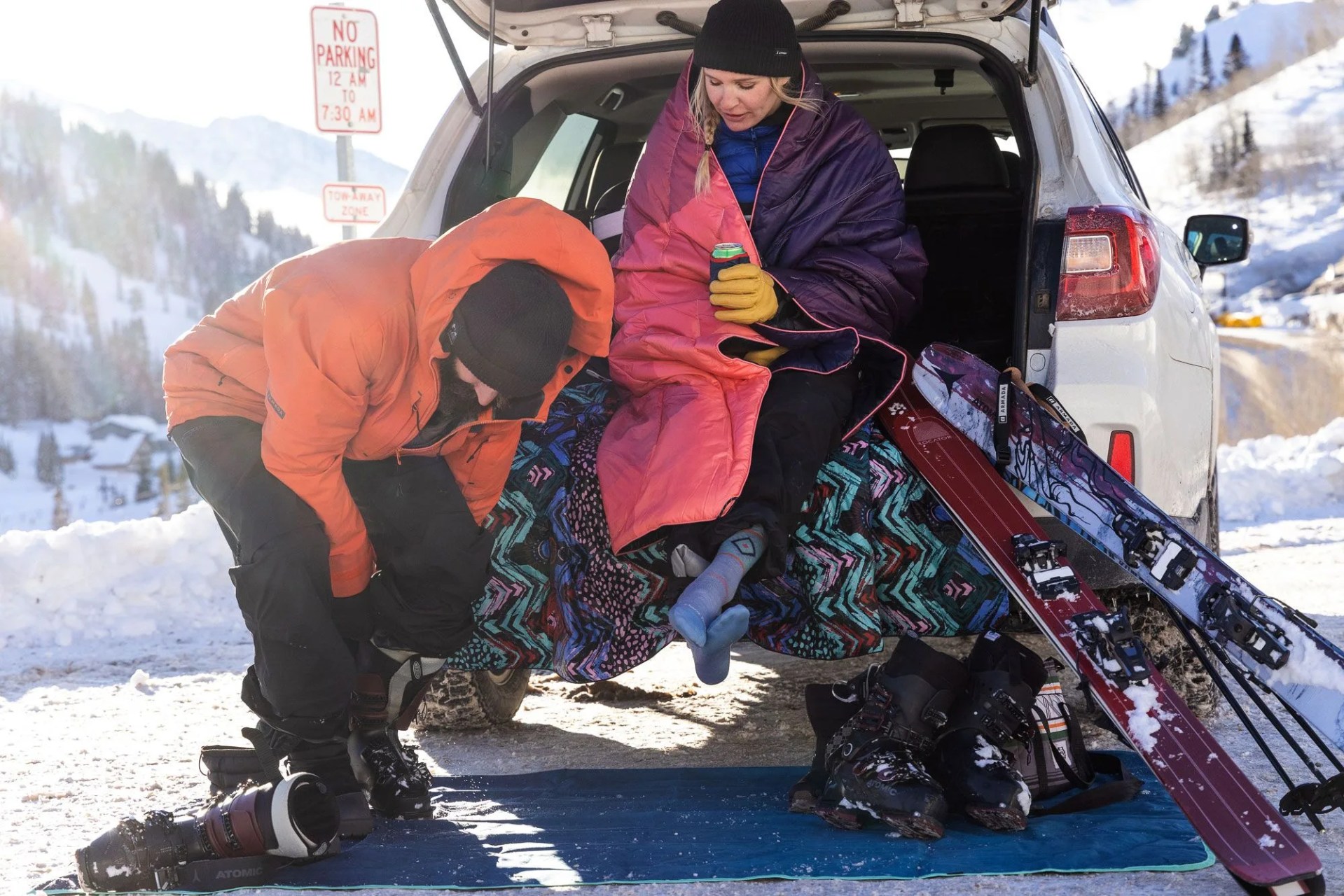 a couple of people with snowboards by a car using rumpl blankets