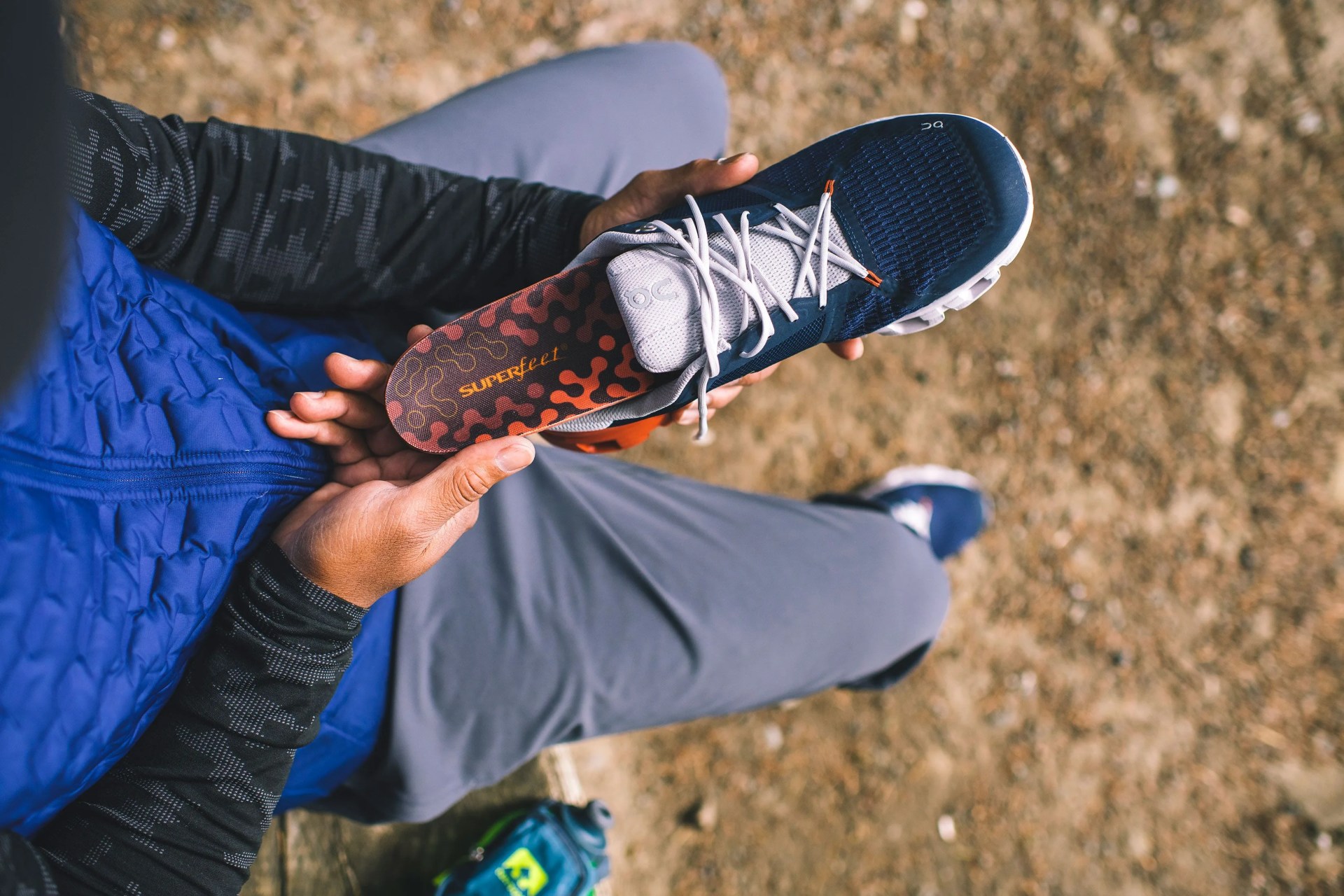 a person holding a blue sneaker with superfeet footbed
