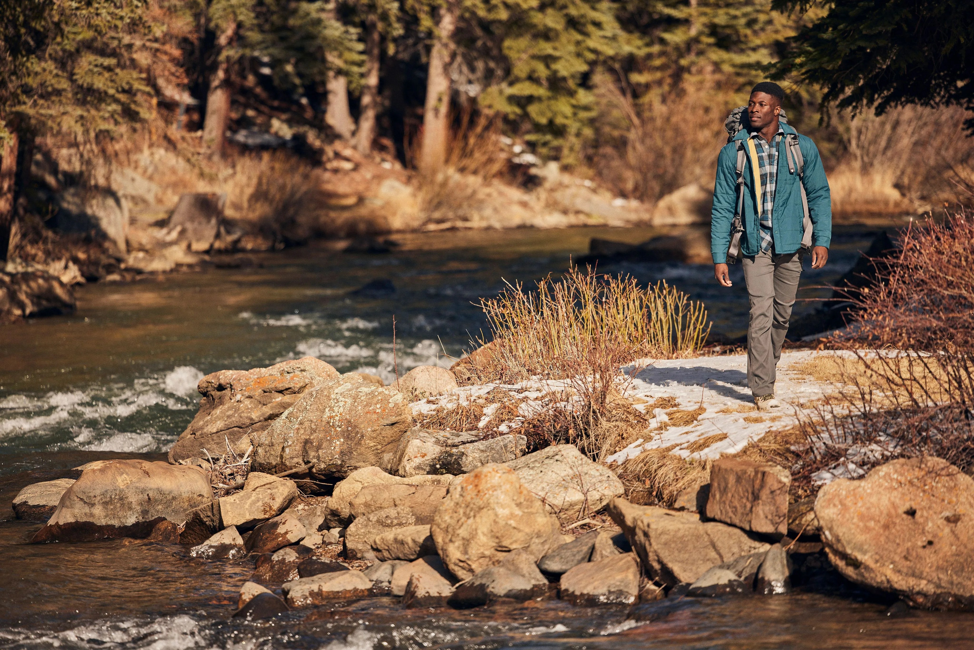 a man walking along pathway by a river wearing wrangler utility pants