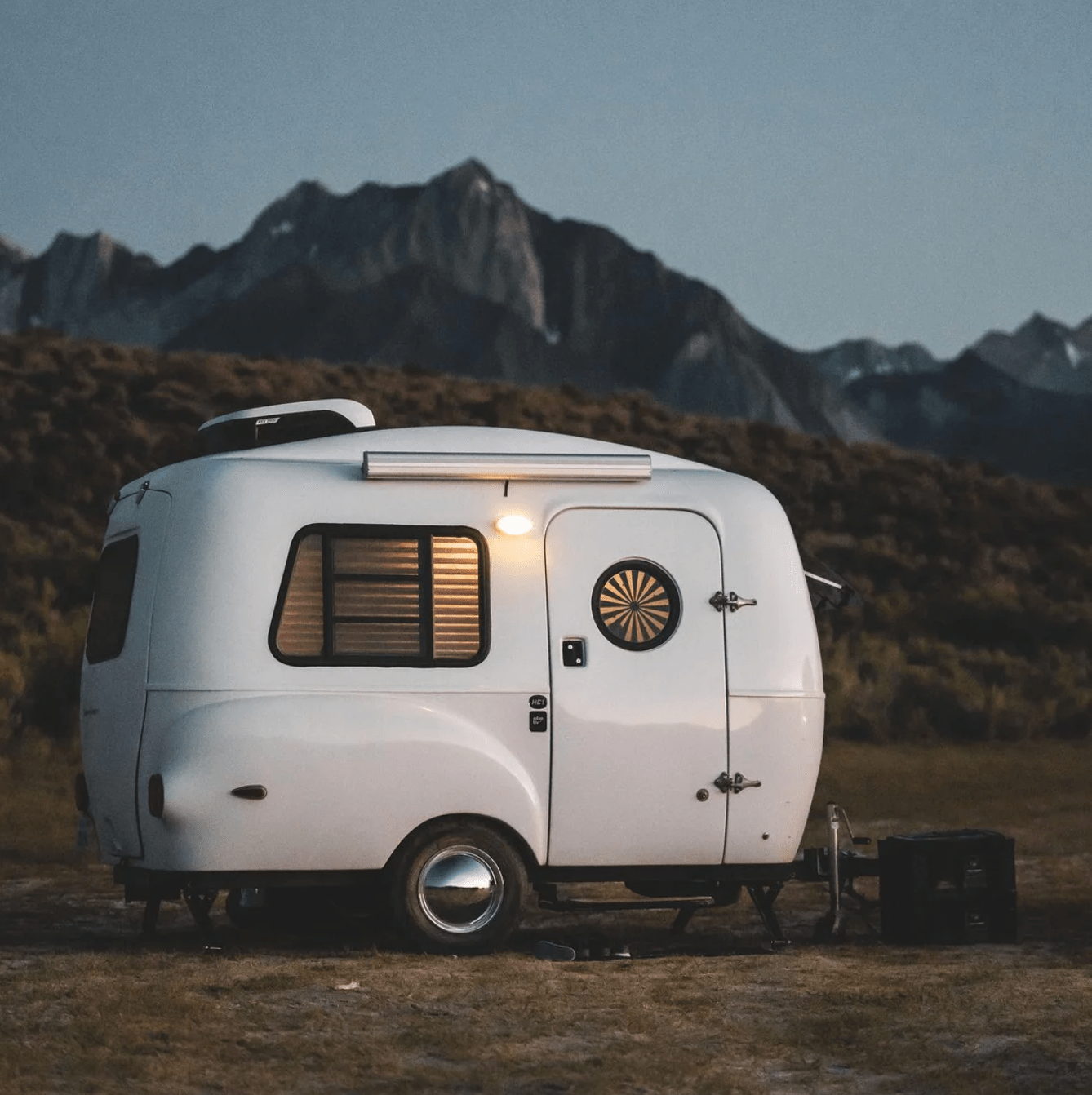 a white camper parked in front of a mountain