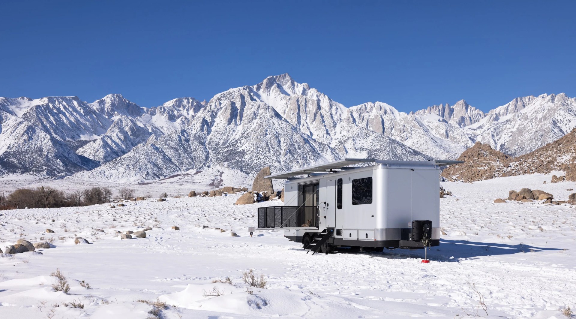 living vehicle trailer in the snow with mountains in the backdrop