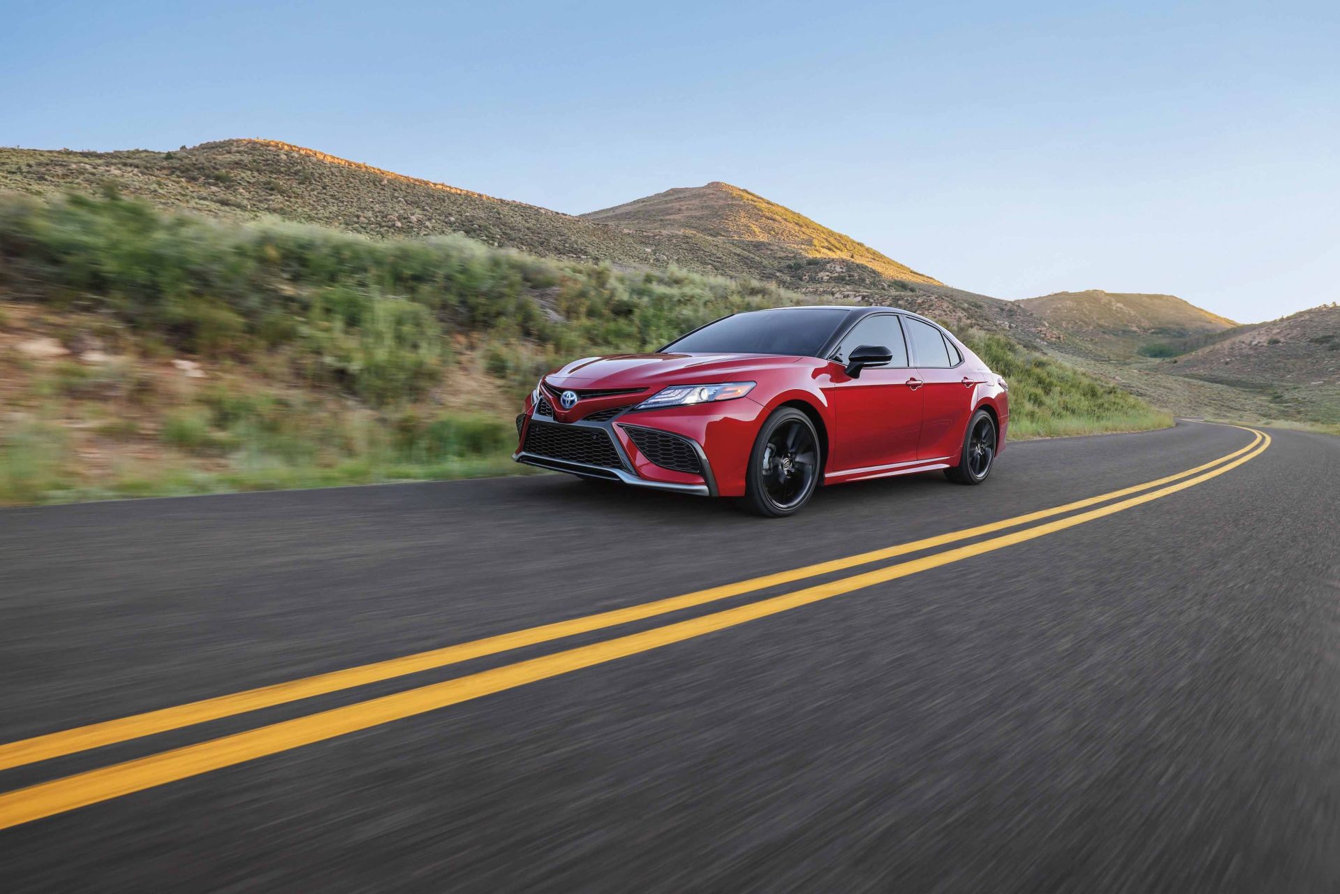 a red sedan driving on a road