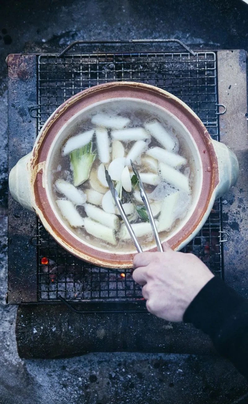 cooking soup on a ceramic pot over a fire