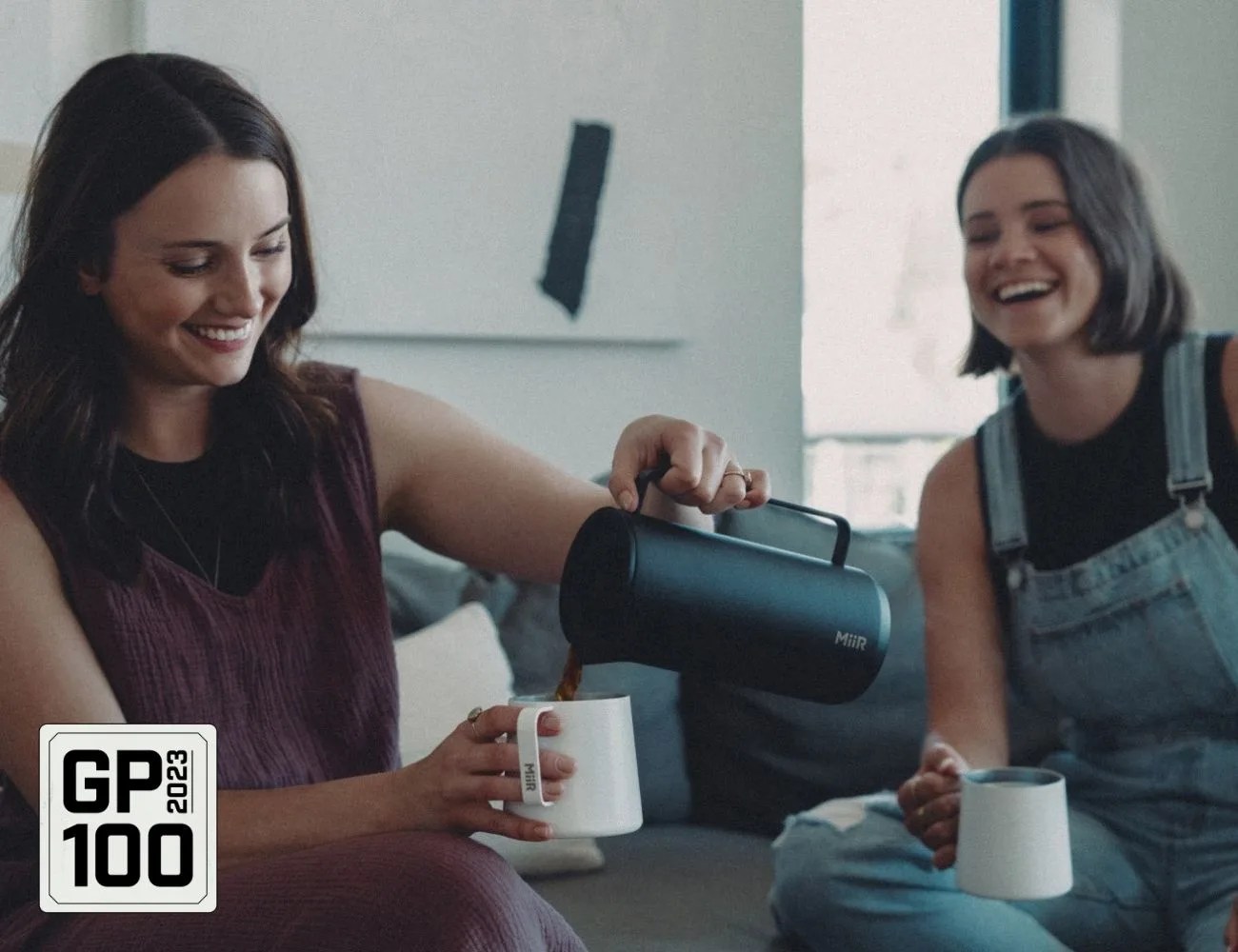 a couple of women holding coffee mugs and smiling