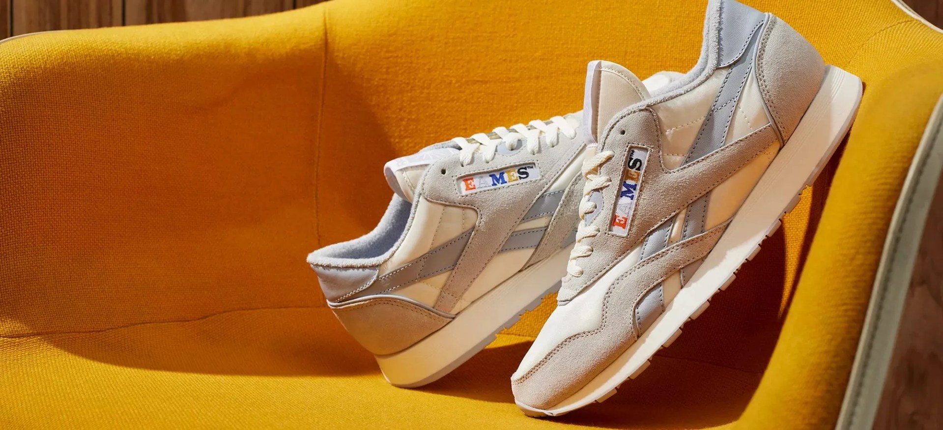 a pair of white reebok eames classic nylon shoes on a yellow chair