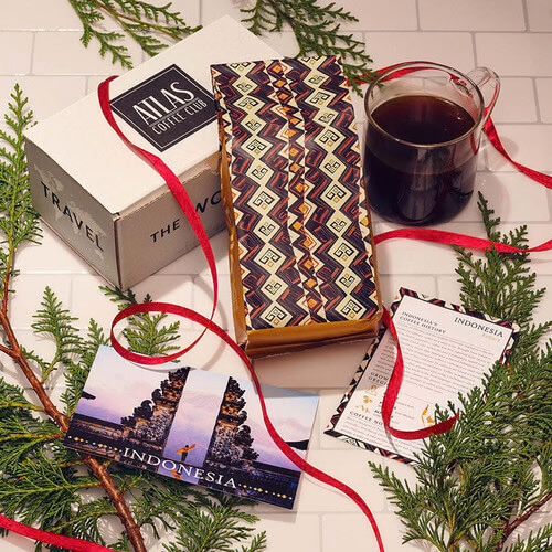 a table with a box, bag of coffee and a cup of coffee on it