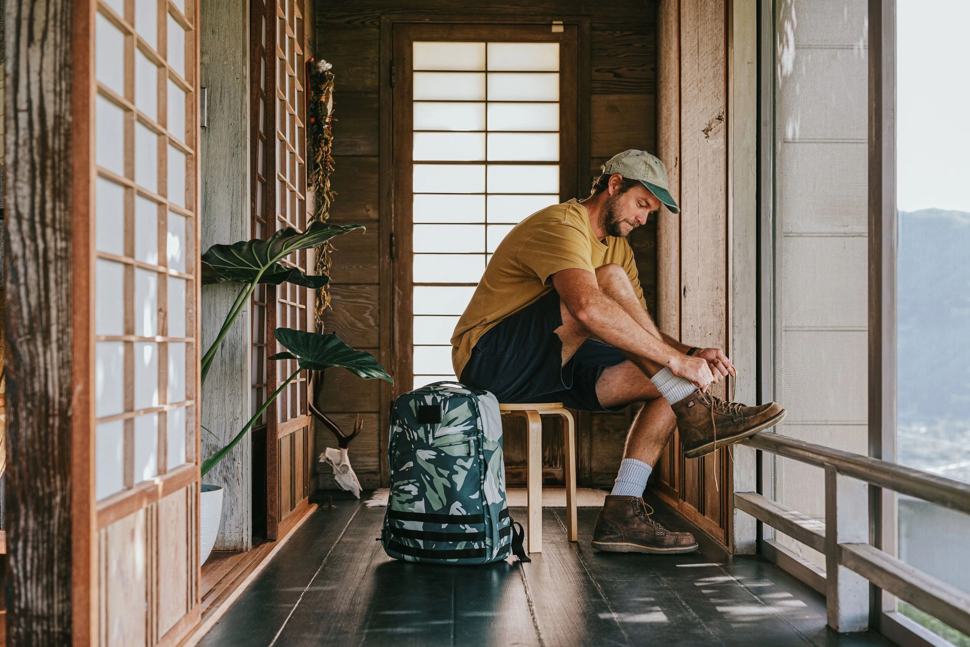 man sitting down tying shoe next to goruck bag