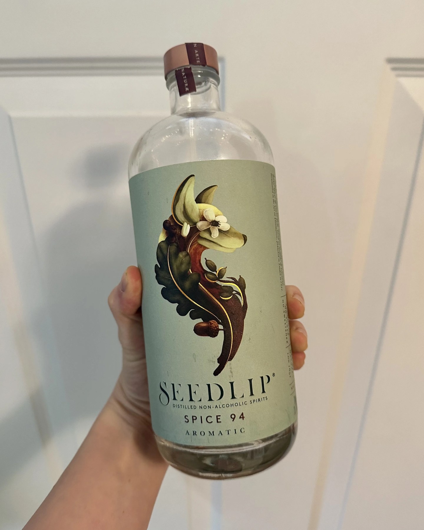 a hand holding a bottle of non alcoholic spirit