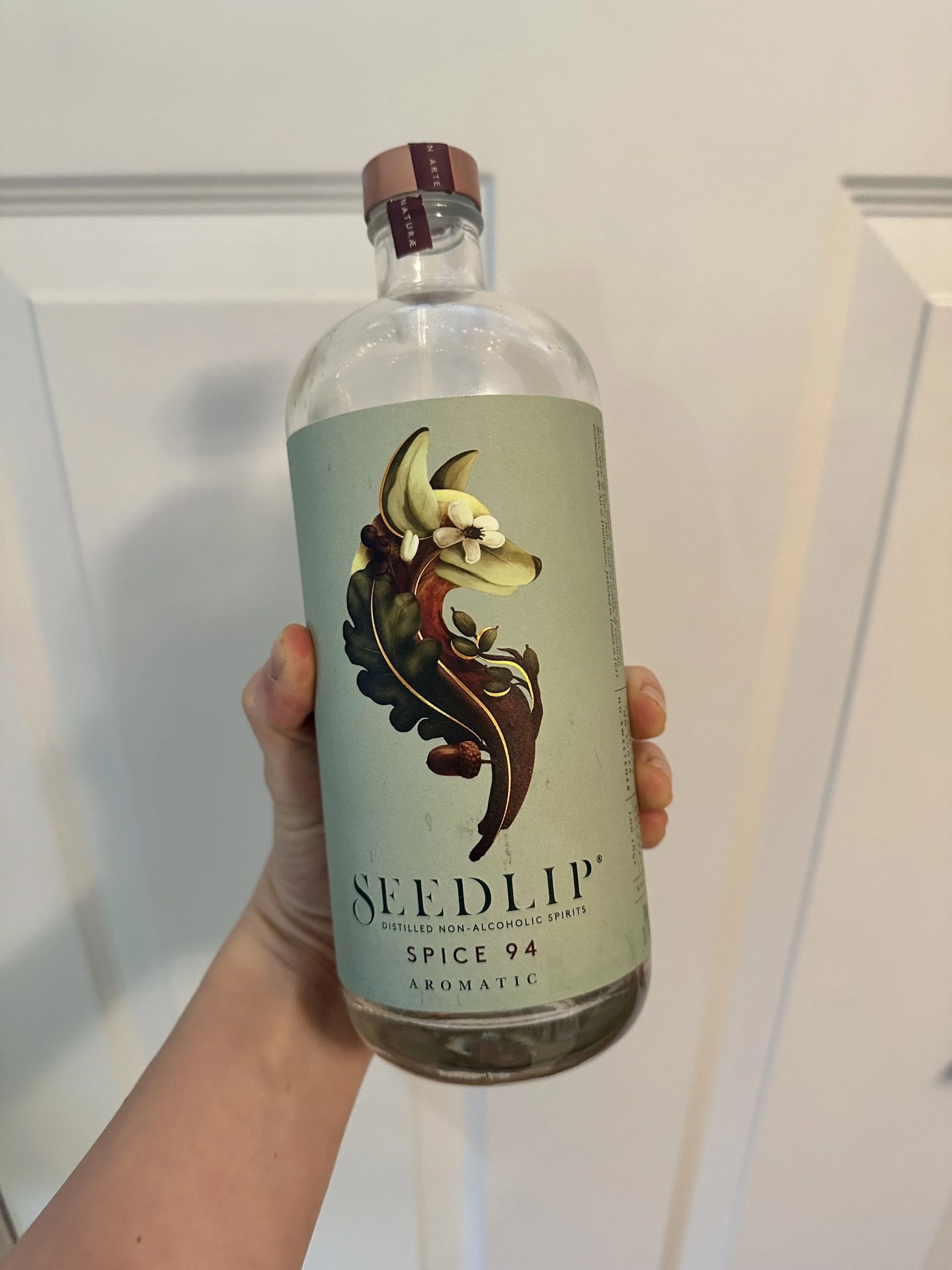 a hand holding a bottle of non alcoholic spirit