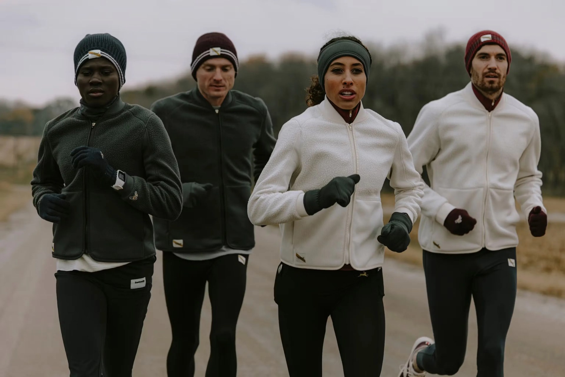 a group of people jogging wearing Tracksmith Fens Fleece