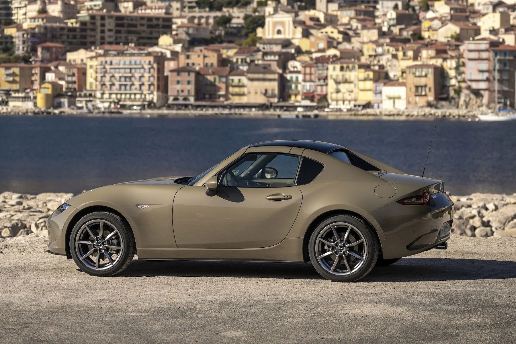 a car parked on a road by a body of water with a city in the background