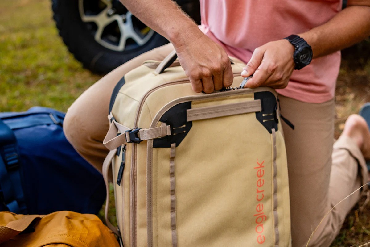 man unzipping eagle creek GEAR WARRIOR XE 4-WHEEL CARRY-ON LUGGAGE